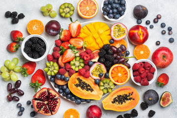 Healthy raw rainbow fruit platter mango papaya strawberries oranges passion fruits berries on oval serving plate on light concrete background, top view, selective focus - obrazy, fototapety, plakaty