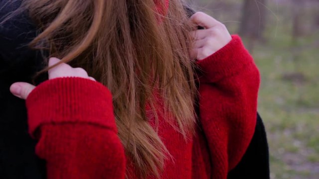 Close up portrait of a young sad brunette girl in a black coat and red sweater