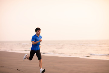 young Man running on  beach at sunset