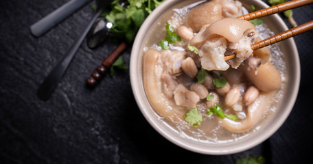 Top view, close up, copy space, Taiwan asian distinctive street food, peanut pork knuckle soup in a beige ivory creamy-white colored bowl isolated on dark shale slate table - Powered by Adobe