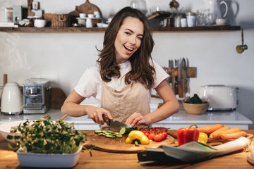 Beautiful young woman wearing apron cooking vegetables