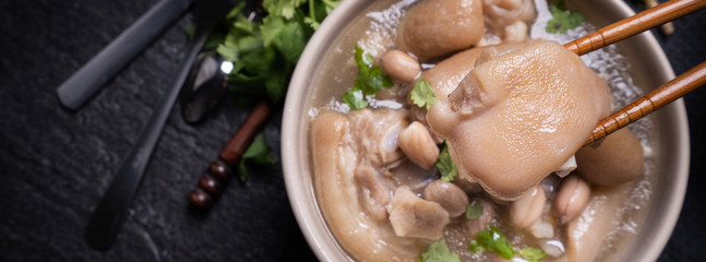 Top view, close up, copy space, Taiwan asian distinctive street food, peanut pork knuckle soup in a beige ivory creamy-white colored bowl isolated on dark shale slate table - Powered by Adobe