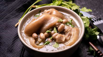 Top view, close up, copy space, Taiwan asian distinctive street food, peanut pork knuckle soup in a beige ivory creamy-white colored bowl isolated on dark shale slate table