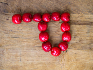  cherry on wooden background as a letter