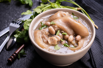 Top view, close up, copy space, Taiwan asian distinctive street food, peanut pork knuckle soup in a beige ivory creamy-white colored bowl isolated on dark shale slate table