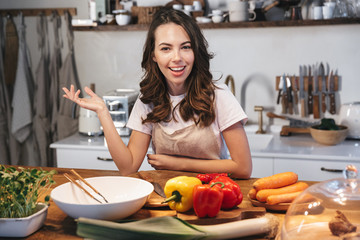 Beautiful young woman wearing apron cooking vegetables