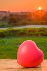 Red heart on wooden with sunrise view