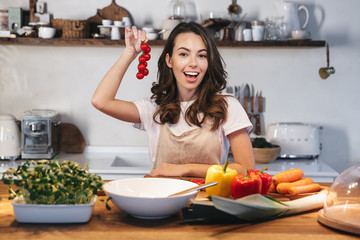 Beautiful young woman wearing apron cooking vegetables