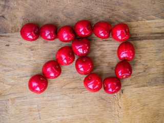  cherry on wooden background as a letter
