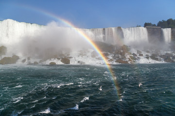 Rainbow over the waterfall, seagulls flying through water mist. Niagara Falls, Canada/USA.