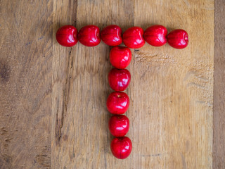  cherry on wooden background as a letter