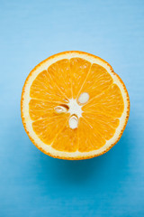 Half of orange on the blue background, close up