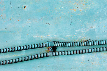 Electrical wire in metal reinforced hose against painted wall