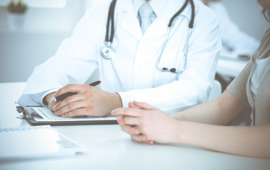 Doctor man and patient are discussing something, just hands at the table. Medicine and health care concepts