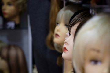 A row of mannequins women on a shelf in a wig shop