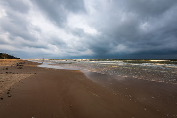 empty sea beach before storm with dramatic clouds and shadows from trees on the sand