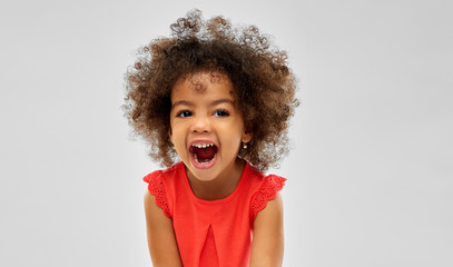 emotion, childhood and expression concept - happy laughing little african american girl over grey...