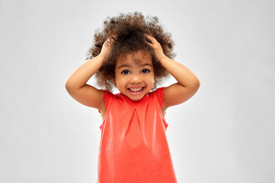 childhood and people concept - overwhelmed little african american girl holding to head over grey background