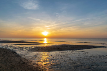 Fototapeta na wymiar orabge colored sunset over calm sea beach water fields