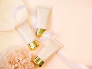 Three shades of concealer in the tube, tonal Foundation for perfect makeup, still life on a soft cream background.