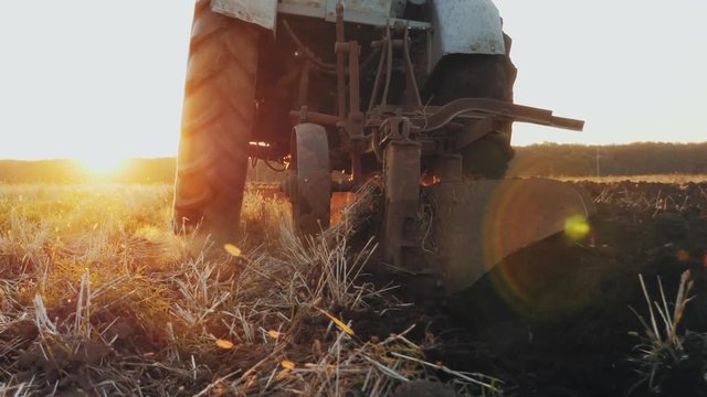 Rear view of an old gray tractor with a harrow