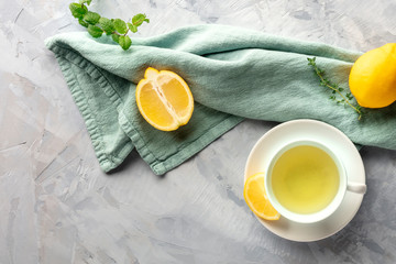 A cup of green tea with lemons and herbs, shot from above with copy space