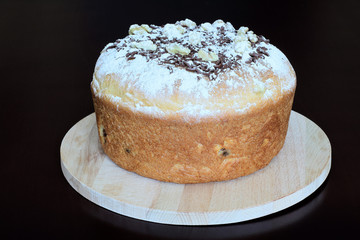 Fresh lush festive bread made from white flour with walnuts on wooden stand on dark background. Concept — culinary recipes, homemade pastries for holiday.