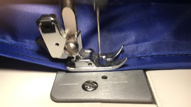 Person stitches cloth on the sewing machine. Cratches the thread on the fabric.