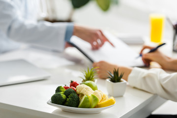 Obraz na płótnie Canvas selective focus of tasty organic fruits and vegetables near women