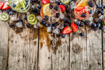 Summer fruits and berry cold cocktail, Lemonade, infused water with blueberries, strawberries, blackberries, kiwi. lemon. Rustic wooden background copy space