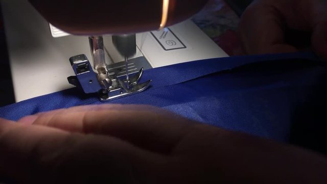 Person stitches cloth on the sewing machine. Cratches the thread on the fabric.