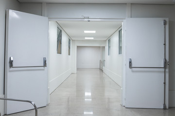 White hospital corridor. Clinic or maternity with white doors stretchers and boards.
