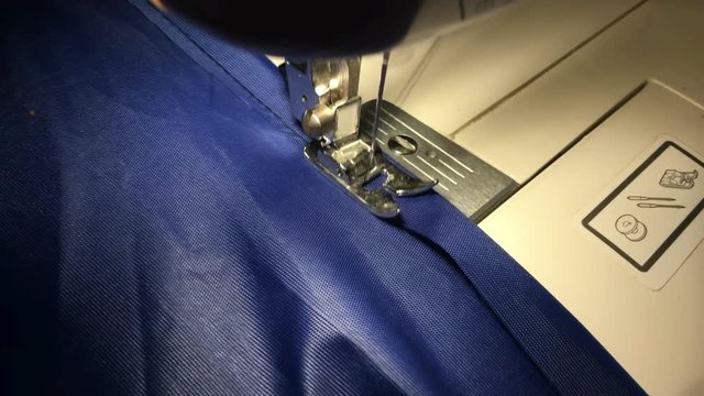 Person stitches cloth on the sewing machine. Cratches the thread on the fabric.