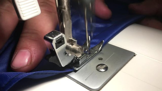 Person stitches cloth on the sewing machine. Cratches the thread on the fabric.