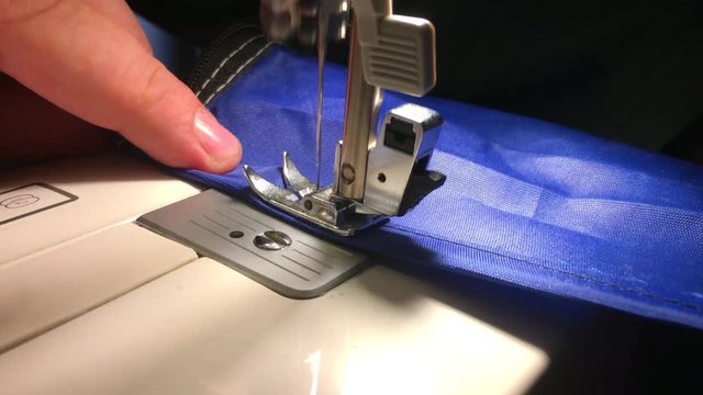 Person stitches cloth on the sewing machine. Cratches the thread on the fabric.