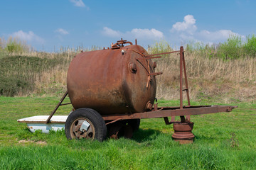 Rusty drinking water tank for cows with a bathtub as drinking trough in a meadow