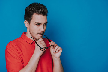 Side view of serious Caucasian guy looking aside on blue background