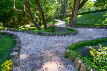 El camino del jardín está lleno de pétalos de flor.