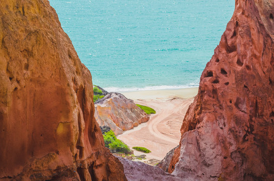 Amazing view of the sea through two rocks. Red tones rock formations. Rock formations called Pico Castelo da Princesa - princess castle at Praia de Coqueirinho, Costa do Conde PB, Brazil. 