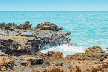 Fototapeta na wymiar Beach rocks, sea water hitting the rocks on the bay. Pointed spongy rocks. Set of rocks near the sea at Praia de Coqueirinho beach, Brazilian northeast beach. Costa do Conde, Conde PB Brazil.