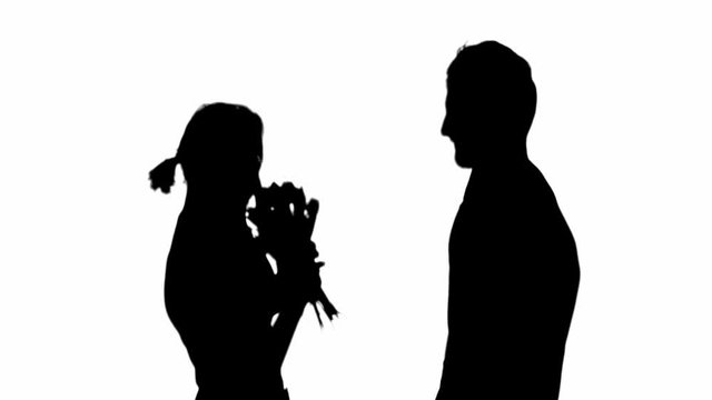 Side view of silhouette of man presenting flower bouquet to woman and embracing isolated on white