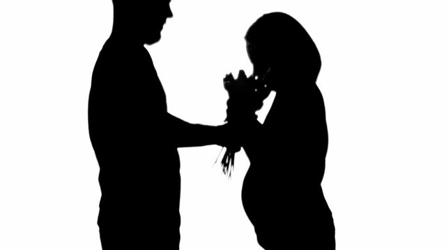 Side view of silhouette of man presenting flower bouquet to pregnant woman isolated on white