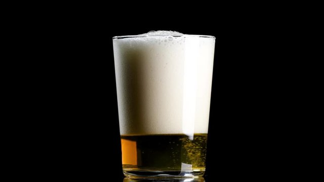 Cerveza cayendo en vaso sobre fondo negro 4k