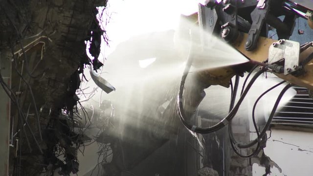 Demolition Machine Spraying Water on Crusher and Debris