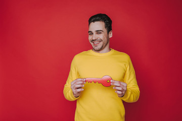 Half length of handsome smiling guy holding paper key in arms