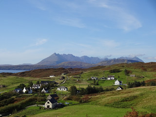 Fototapeta na wymiar Blick über die Häuser im Dorf Tarskavaig in Sleat hinüber zu den Cuillins Bergen auf der Isle auf Skye in Schottland