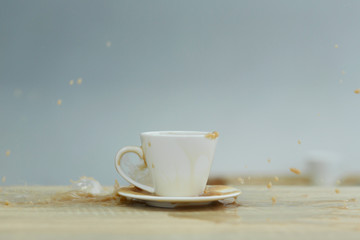Splash in white cup of coffee on wooden table