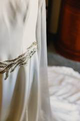 Detail of a white wedding dress hanging.