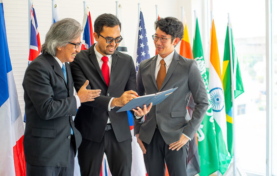 Group of business or political men look happy during the discussion of their work and they stand in front of various international flags