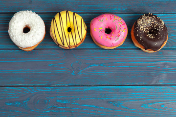 Colorful fresh donuts on dark blue wooden surface